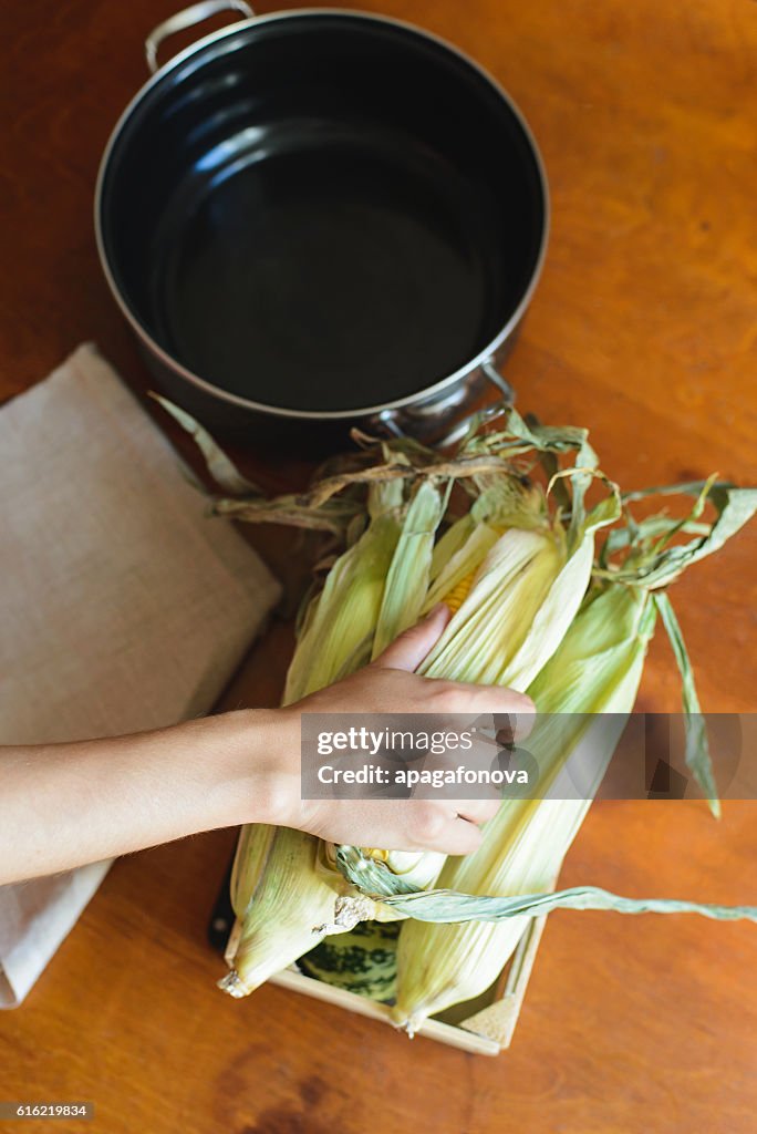 Top view of woman prepares corn for cooking in bowl