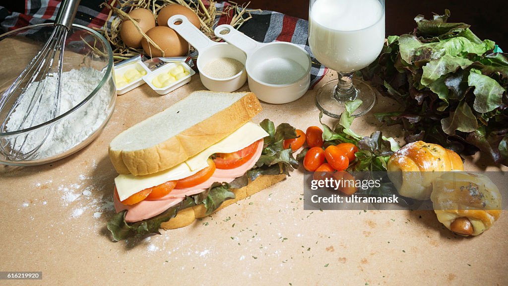 Big sandwich with ham, cheese and vegetables on woodboard