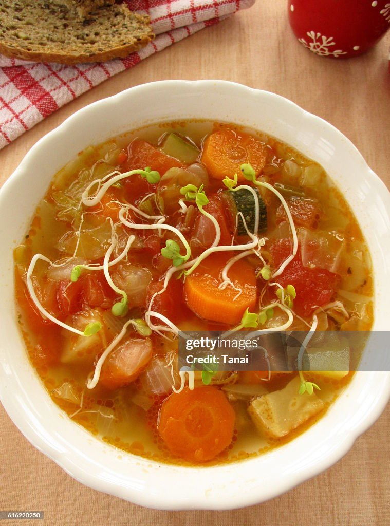 Vegetable soup with sprouts in white bowl