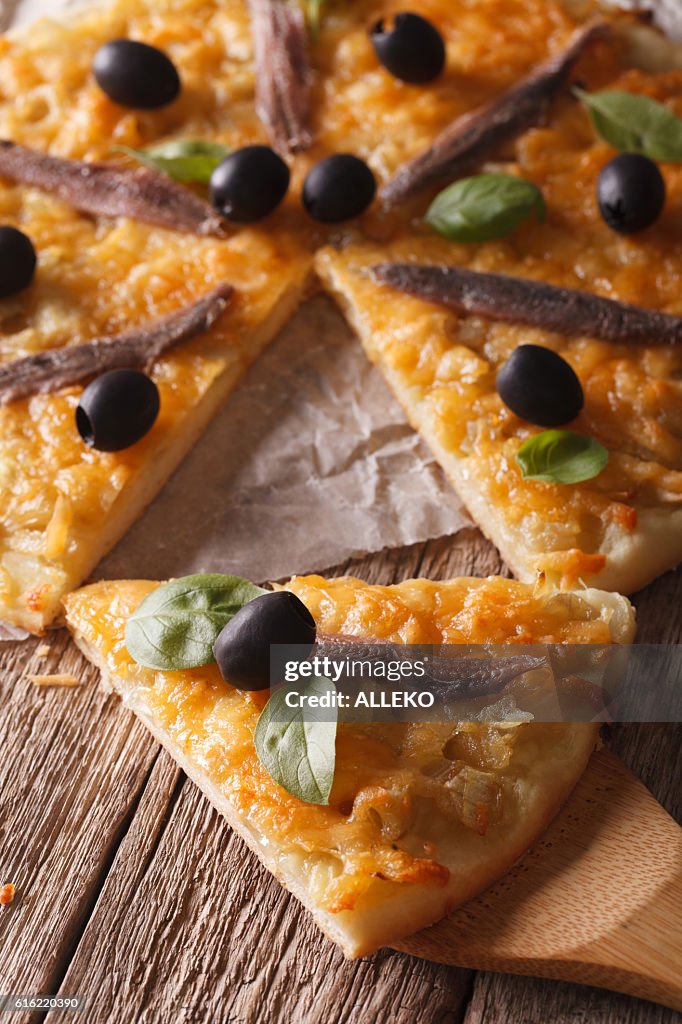 French pizza with anchovies and onions close-up. vertical