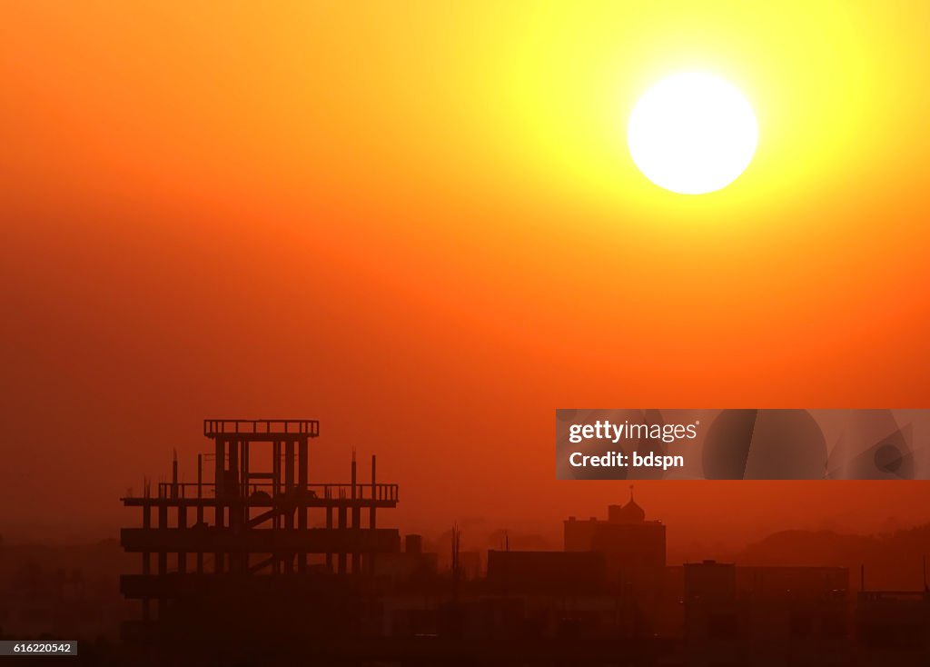 Setting sun behind construction building