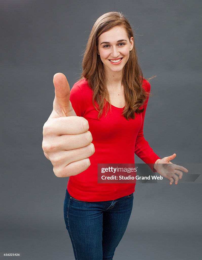 Smiling young woman with thumbs up for symbol of satisfaction