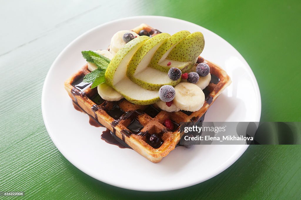 Wafers with chocolate, banana, a pear, berries and mint