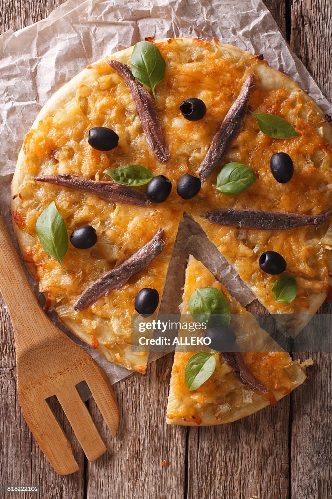 Geschnittene Pizza mit Sardellen und Zwiebeln aus nächster Nähe. Vertikale Ansicht von oben