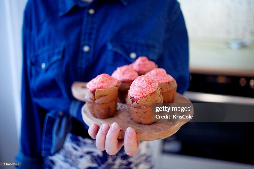 Mädchen hält Teller mit frischen, warmen muffins, verschwommene Hintergrund