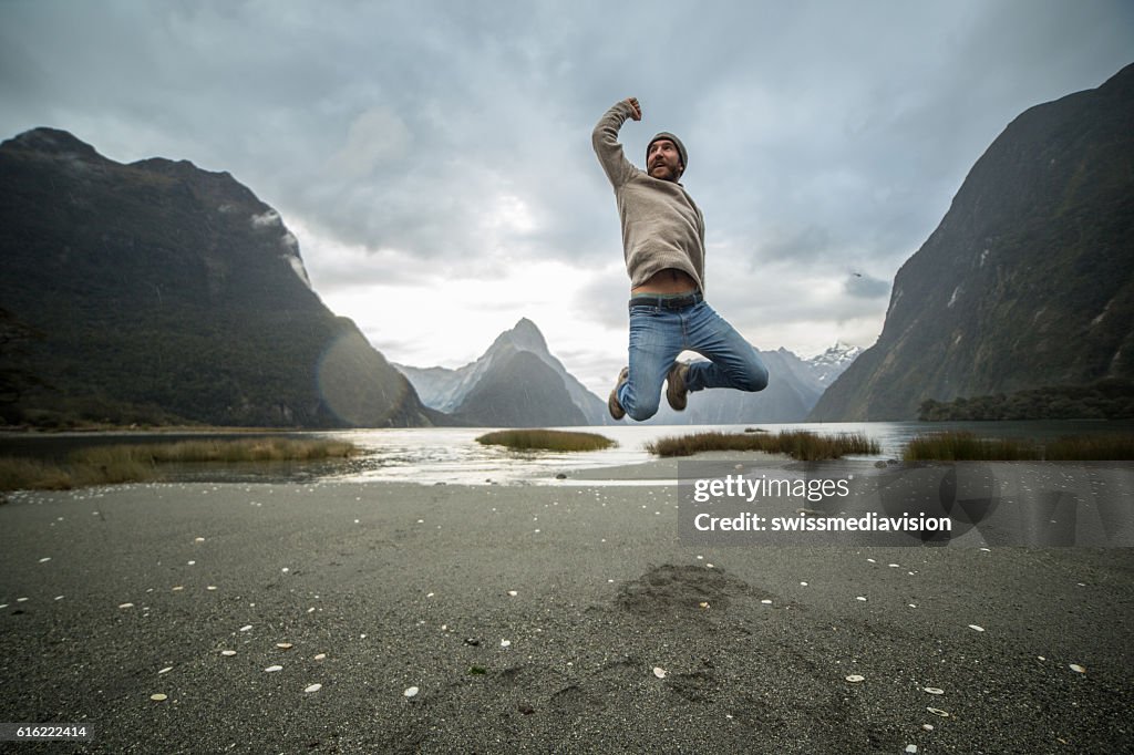 Young man jumps in front of Mitre peak, New Zealand