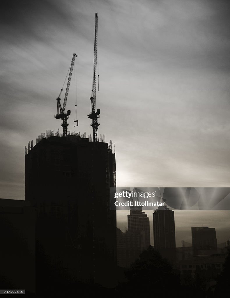 Silhouette Industrial construction cranes and building