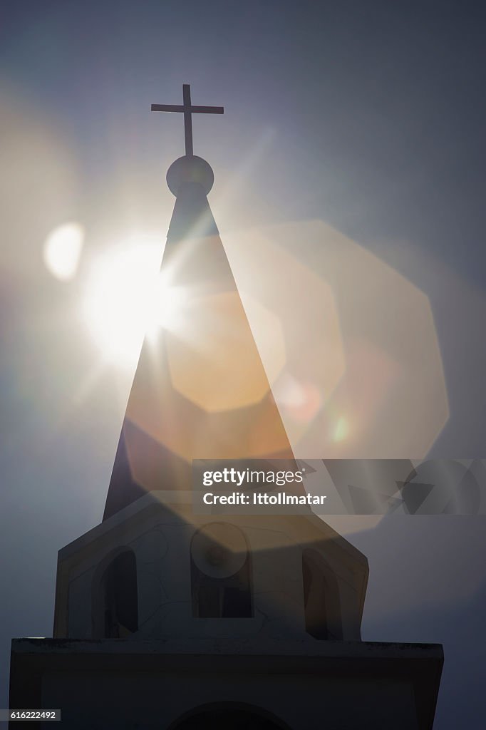 Steeple of the church with a sun at background