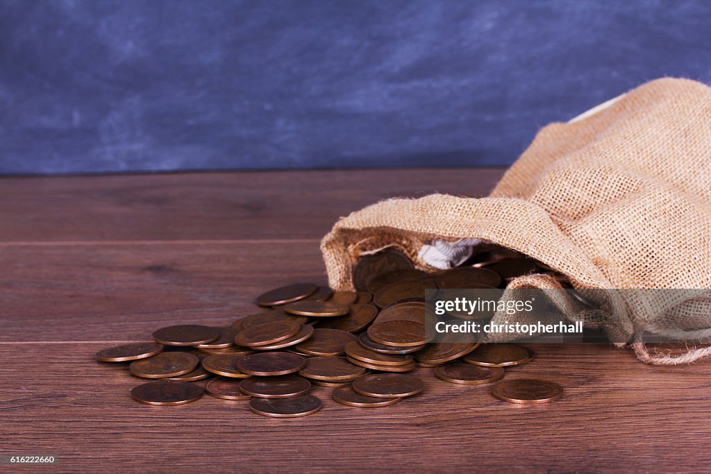 Beutel mit Münzen über eine Holzoberfläche verschüttet