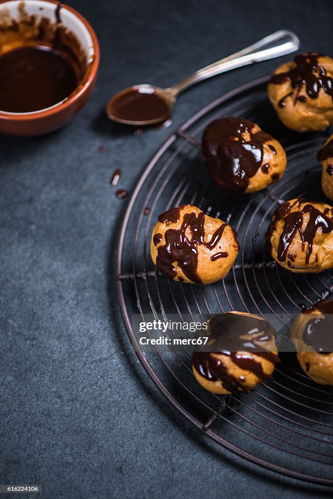 Decorating profiteroles with melted hot chocolate