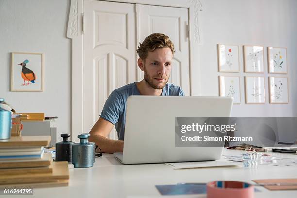 young businessman using laptop at work - am schreibtisch mit laptop stock-fotos und bilder