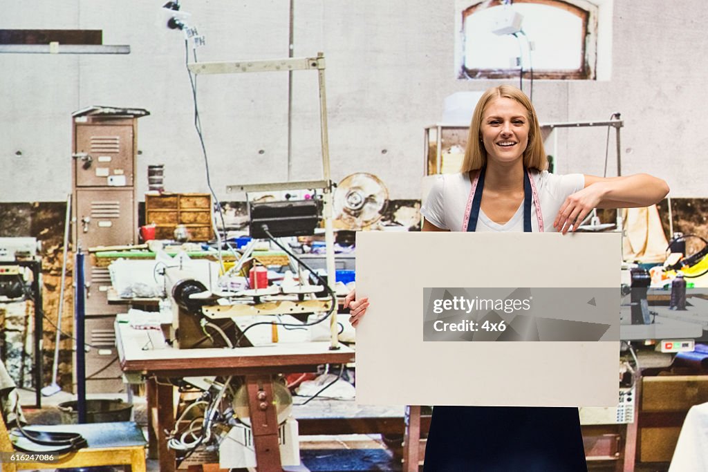 Lächelnde Arbeiter halten Plakat in der Textilindustrie