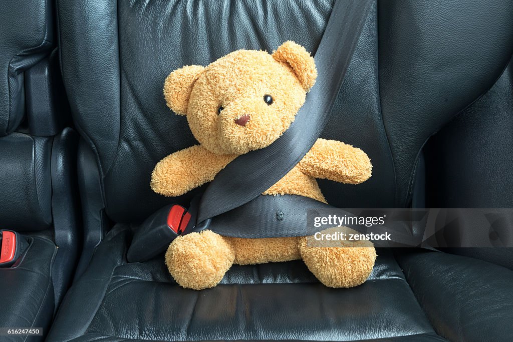 Teddy bear fijado en el asiento de atrás de un coche