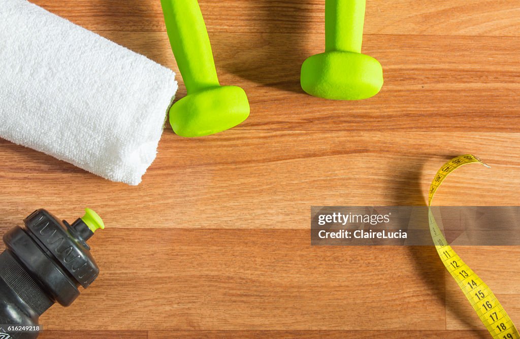 Fitness concept with dumbbells, water bottle, measuring tape, towel on