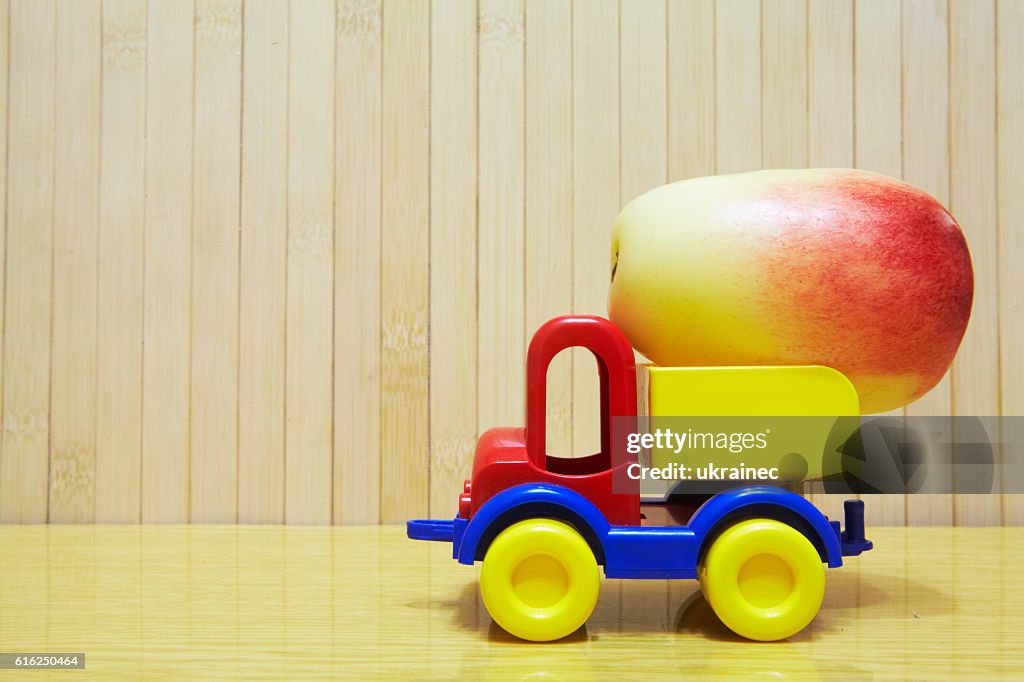 Toy plastic car with red apple