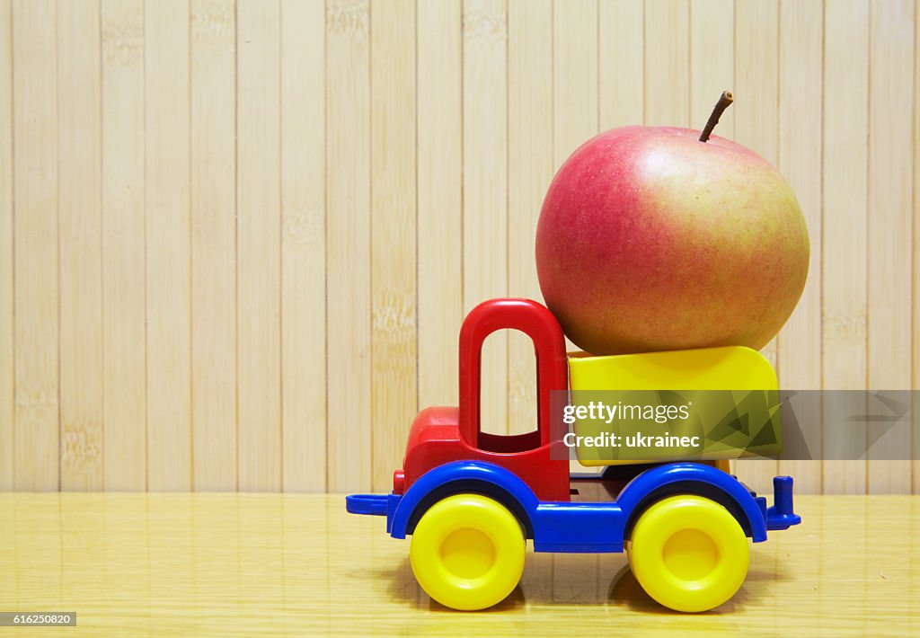 Toy plastic car with red apple