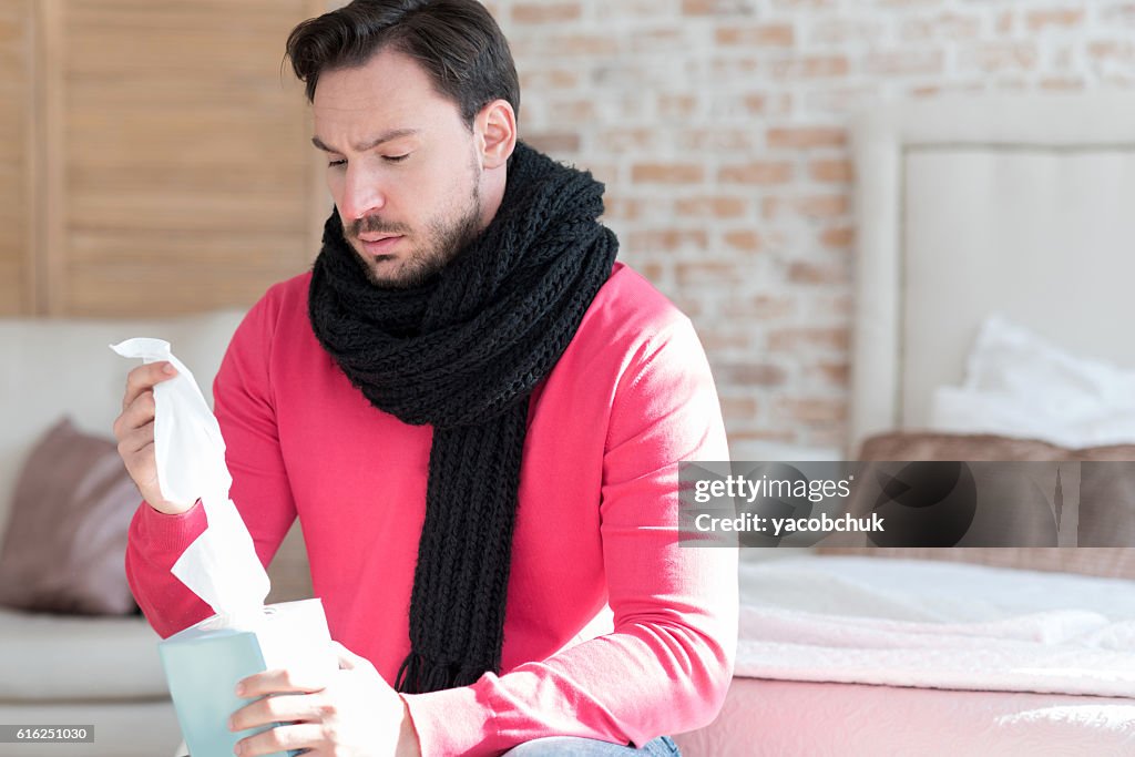 Sad young man holding a box of paper tissues