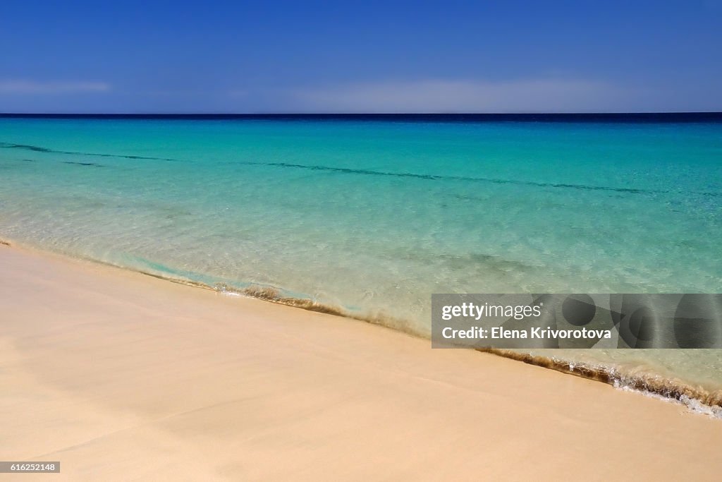 Sea with crystal water and golden sand on the beach.