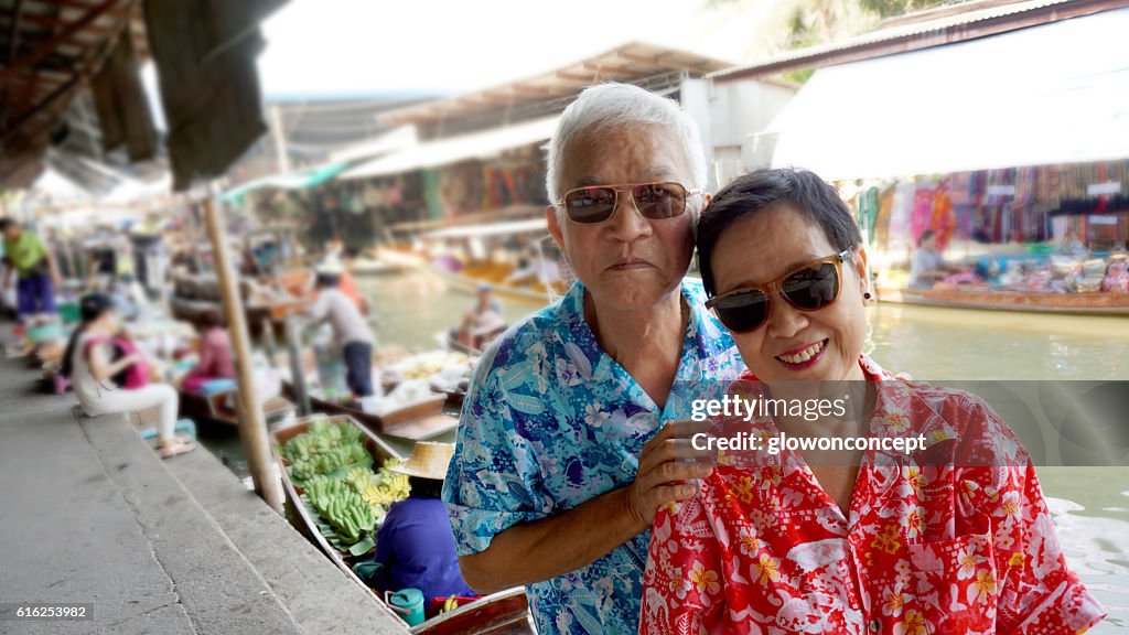Asian senior couple travel to thailand floating market