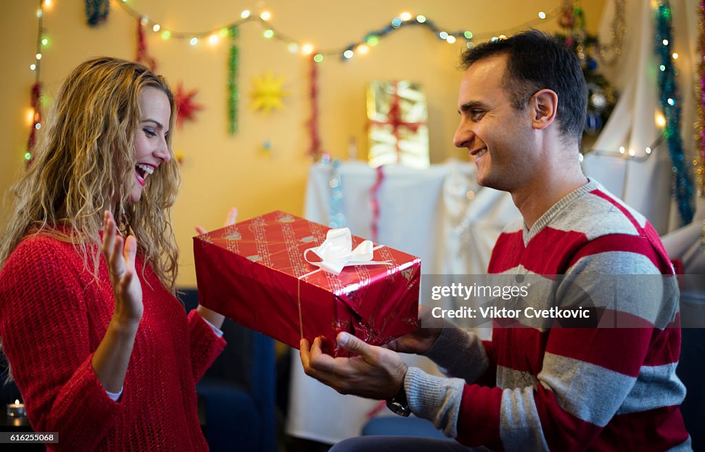 Suprised woman taking a gift from husband. Happy New Year.