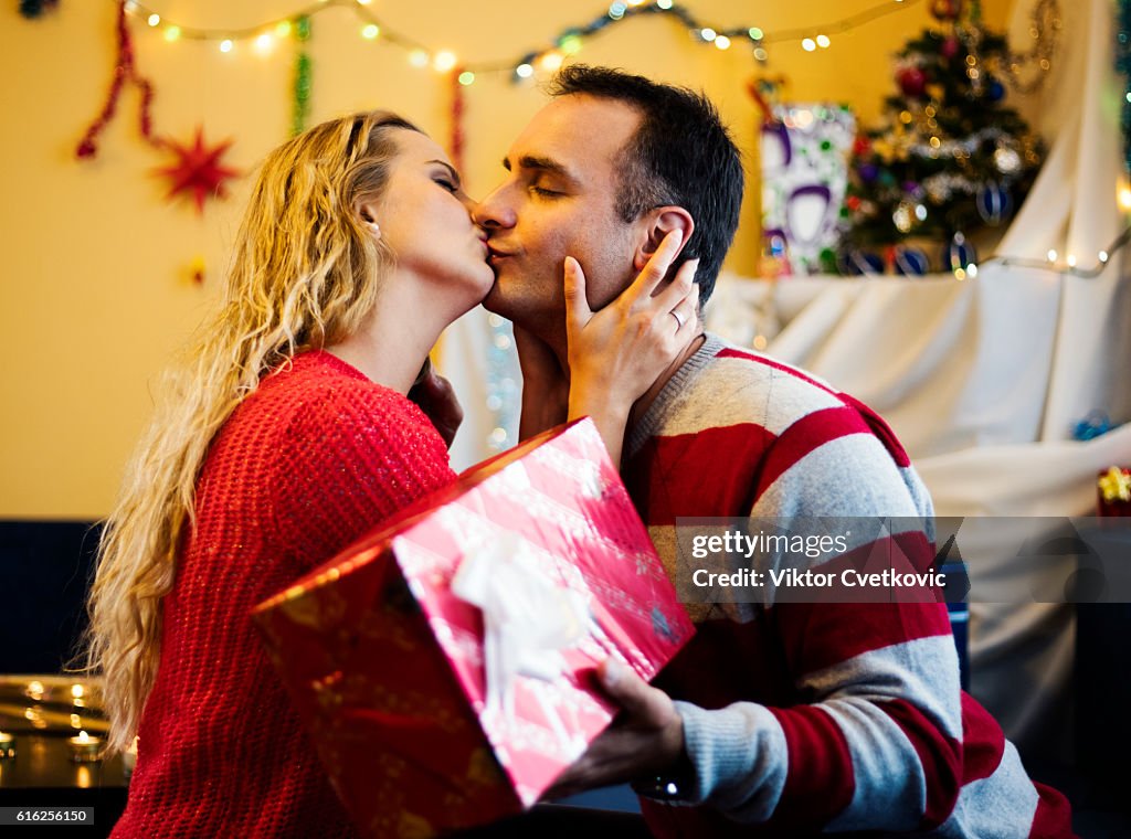 Cute couple with gift kissing of New Year eve.