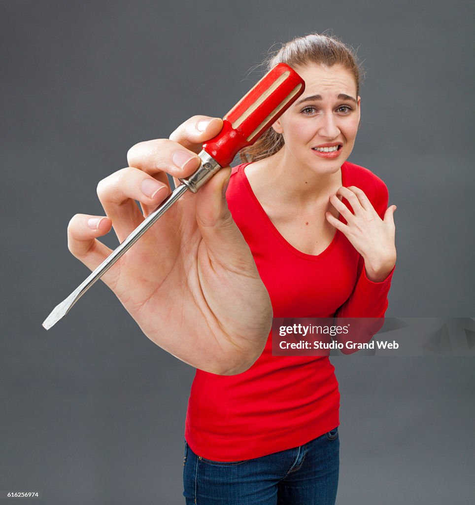 Scared beautiful young woman with symbolic screwdriver for DIY fear