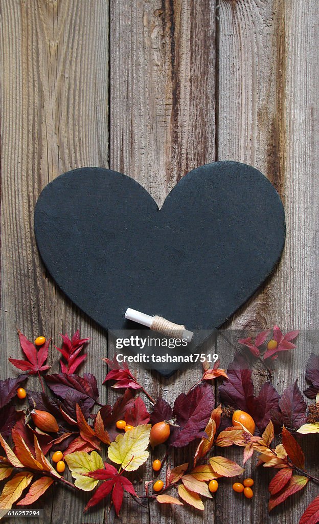 Background with autumn leaves, slate heart and chalk