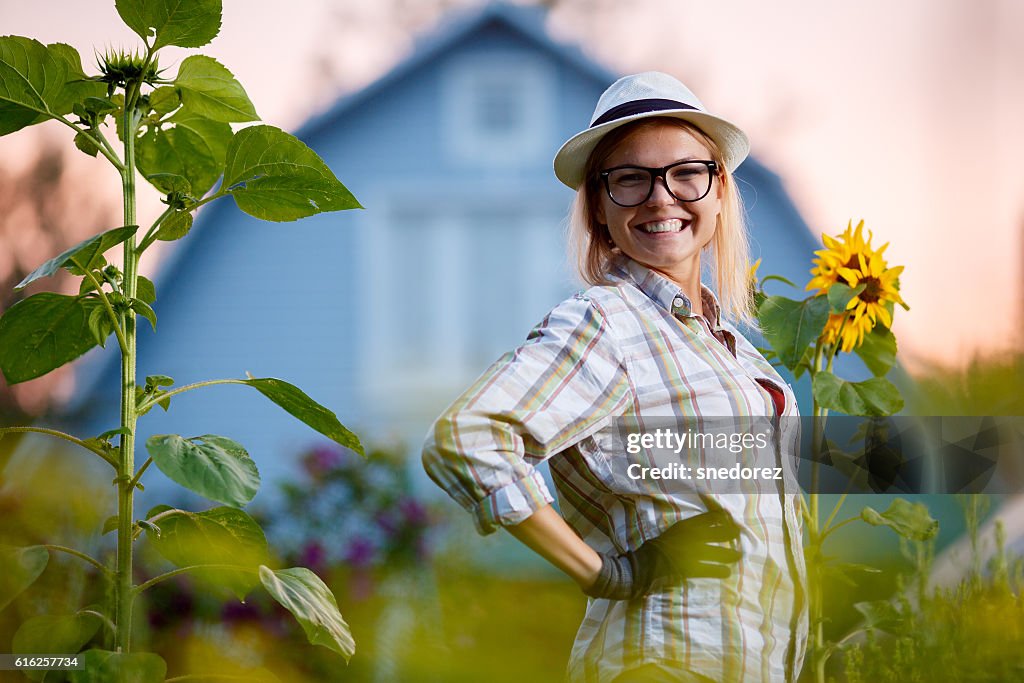 Happy young gardener posing in garden before her cottage