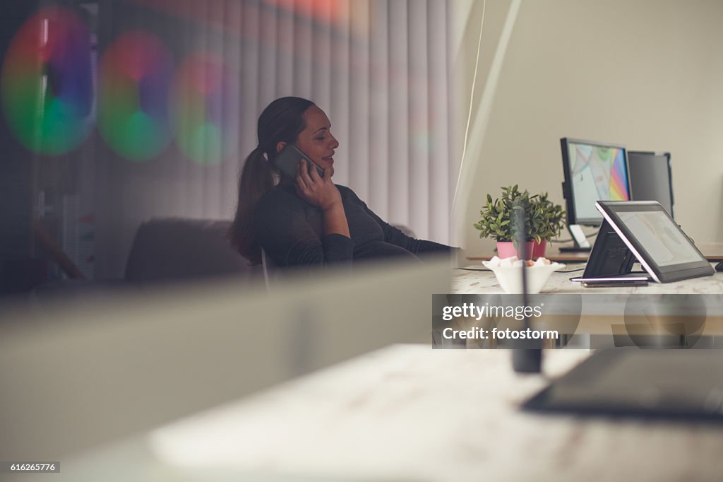 Pregnant woman talking on cellphone in office