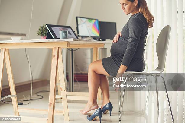 pregnant woman taking off her shoes - work shoe stock pictures, royalty-free photos & images