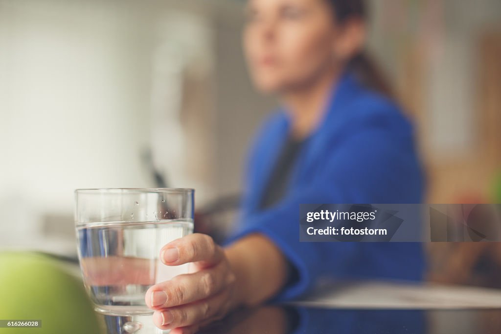 Businesswoman reaching for glass of water