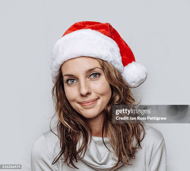 studio portrait of woman wearing santa hat - weihnachtsbilder stock-fotos und bilder