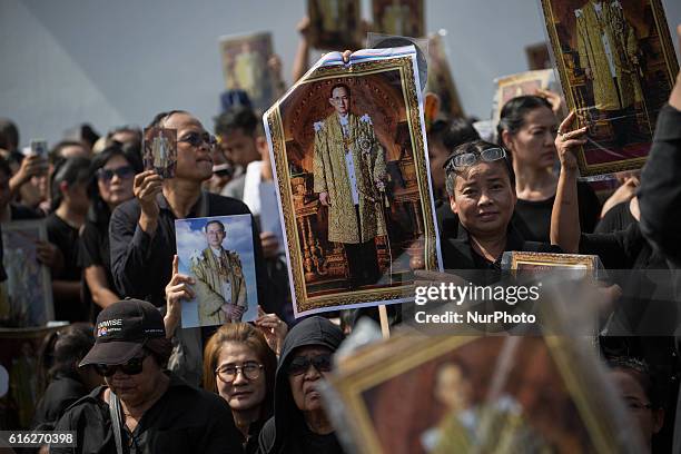 Mourners dressed in black gathers around the Grand Palace while carrying several portraits of the king as they wait to perform the Royal Anthem at...