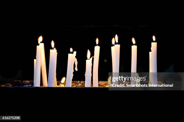 several candlelights lit up against black background - dark room foto e immagini stock