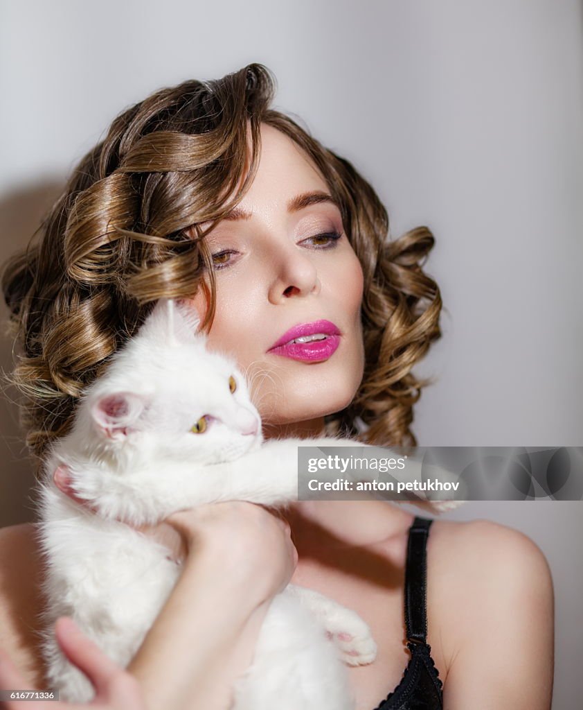 Beautiful girl with a white fluffy cat in her arms.