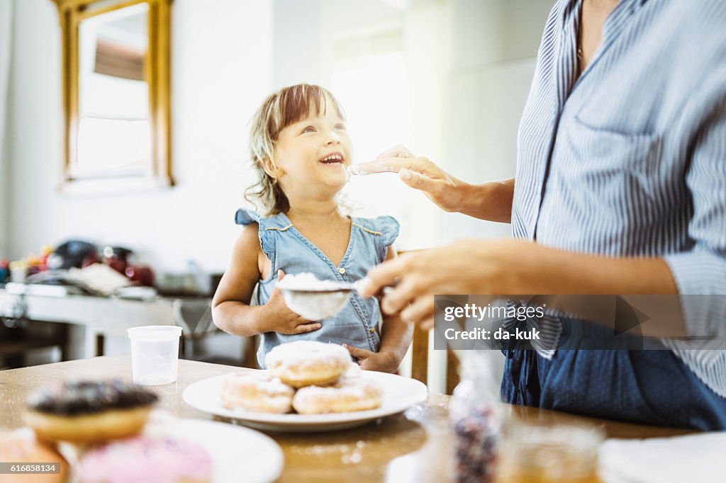 Mother and daughter making sweet donuts in the kitchen