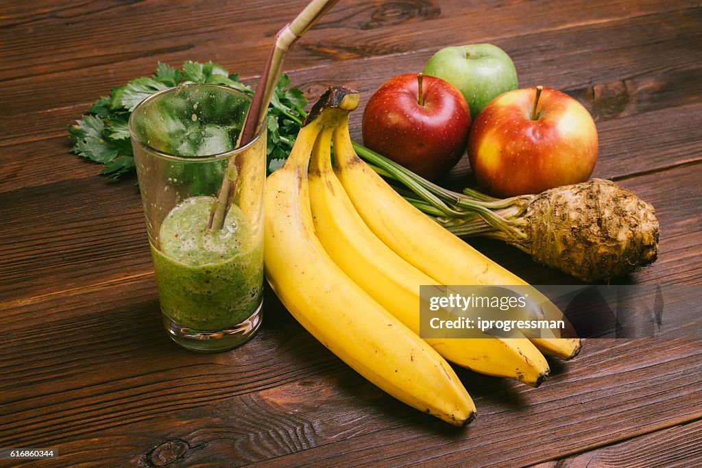 Half full glass of smoothie with straw, banana, celery root