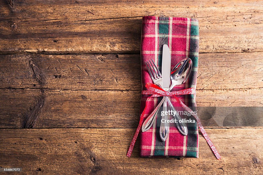 Cutlery on checkered napkin with ribbon branch on wooden background