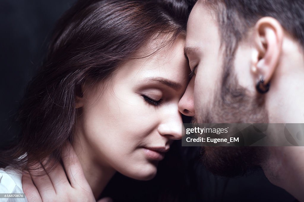 Beautiful cute loving couple in a studio with dark walls