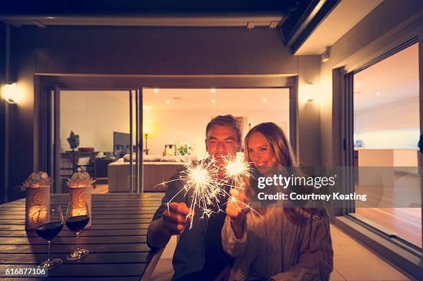 couple with sparklers outside their home at night. - happy new year 2016 stock pictures, royalty-free photos & images