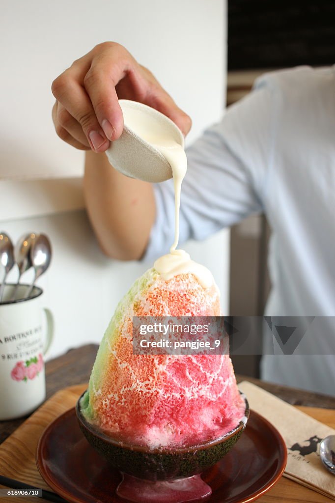 Pouring sweetened condensed milk on top of shaved ice