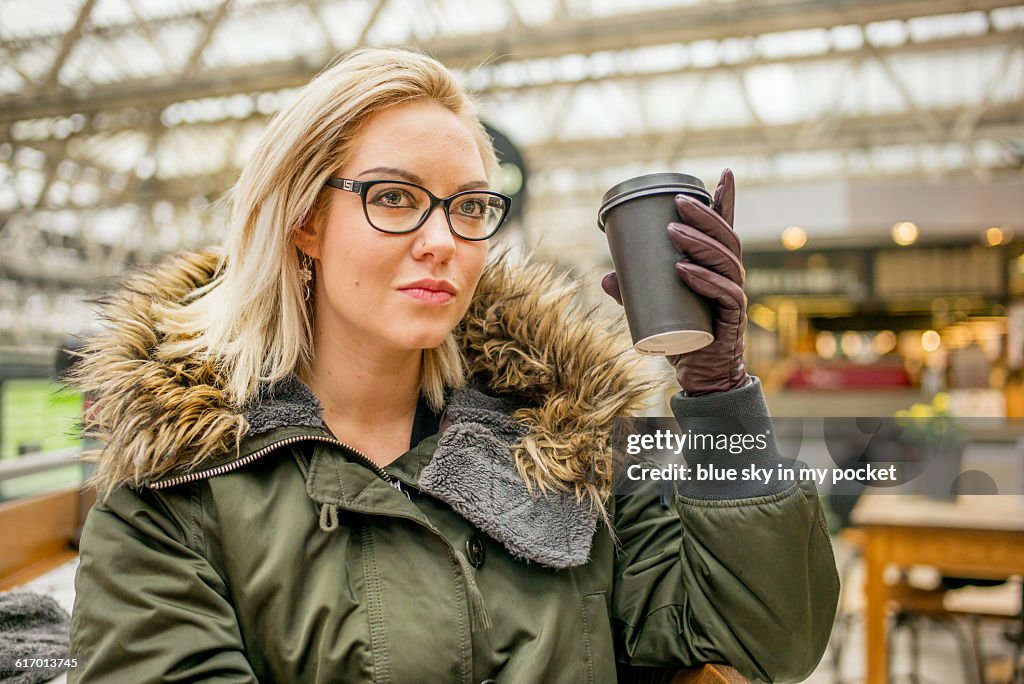 A woman in winter clothes drinking coffee