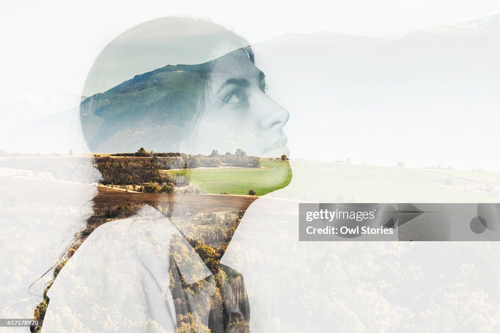 Multiple exposure of a young woman and mountain landscape