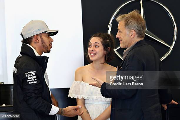 Lewis Hamilton of Great Britain and Mercedes GP talks with actors Christoph Waltz and Rosa Salazar in the garage during final practice for the United...