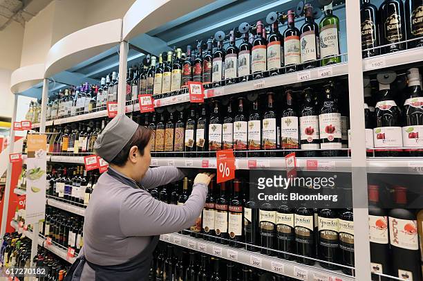 An employee arranges bottles of wine on shelves inside a Victoria supermarket operated by Dixy Group PJSC in Moscow, Russia, on Friday, Oct. 21,...