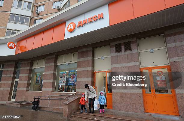 Customer carries a bag of goods while leaving a supermarket operated by Dixy Group PJSC, with two children in Moscow, Russia, on Friday, Oct. 21,...
