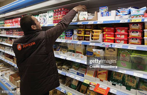 An employee wearing a branded uniform arranges products in the dairy section inside a supermarket operated by Dixy Group PJSC in Moscow, Russia, on...