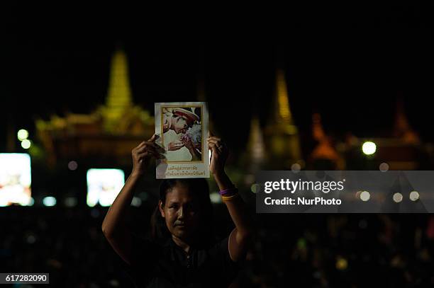 Thai mourners wearing black hold portraits of late Thai King Bhumibol Adulyadej during the royal religious praying rites for the king outside Grand...