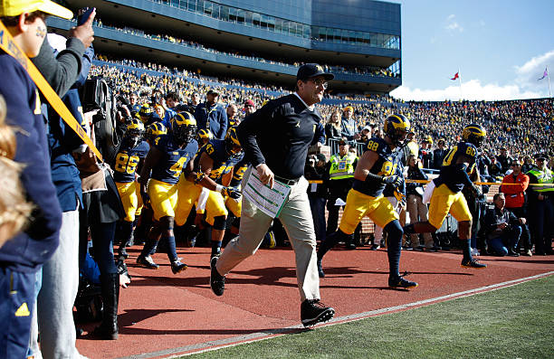 Head coach Jim Harbaugh of the Michigan Wolverines leads the team onto the field to play the Illinois Fighting Illini on October 22, 2016 at Michigan...