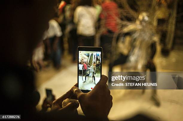 Man takes a video of performance artist Jelili Atiku during the opening of the Lagos Photo festival in Lagos on October 22, 2016. Lagos Photo was...
